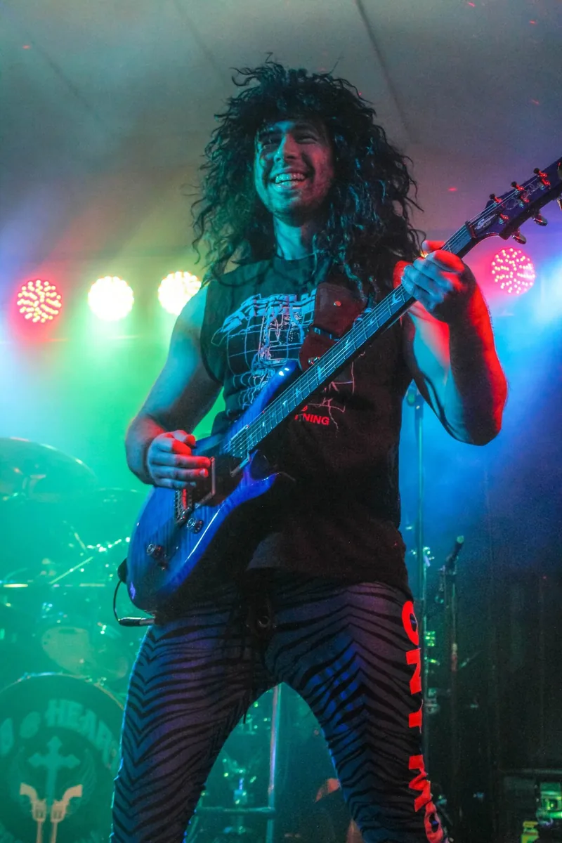 Guitarist mid-solo in green stage light